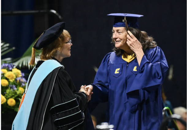 Lori Coletta shakes hands with College of Health, Education and Professional Studies Dean Valerie Rutledge as she crossed the McKenzie Arena stage during Graduate School commencement.
